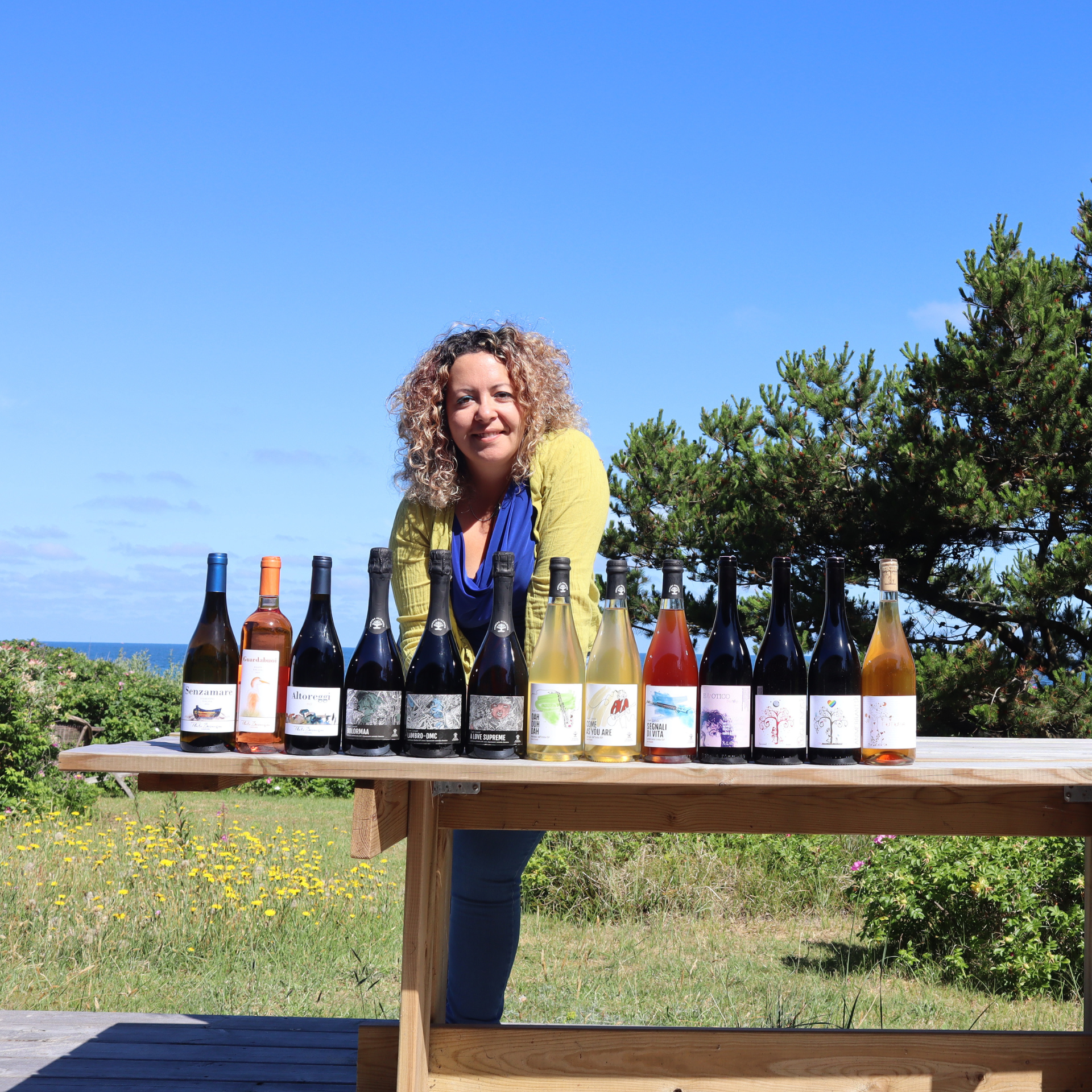 About Trellising - in photo Susanna Camerlengo, the founder of Trellising with the wine bottles of the artisanal winemakers followed by Susanna